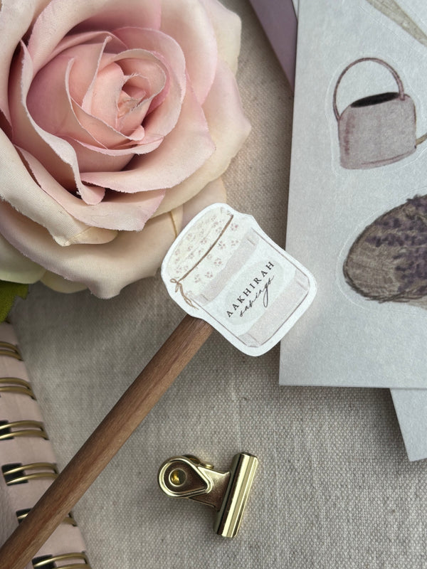 A close up of floral jar aakhirah savings sticker from A5 islamic sticker sheet. Dusty pink rose in background