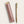 A gold-colored ballpoint pen with a gold clip and nib, displayed next to its matching dusty rose pink leather sleeve on a light beige background.