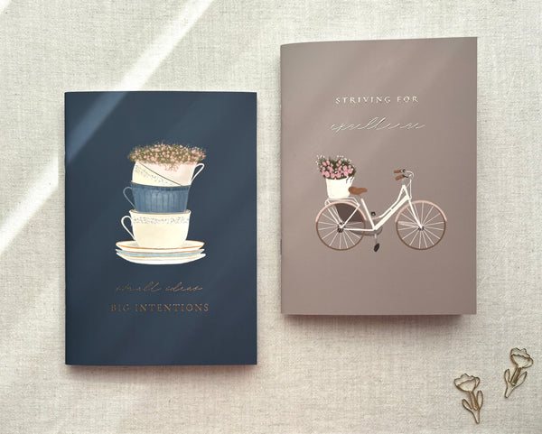 Set of two floral Islamic exercise books with bicycle and teacup illustrations and gold-foiled motivational quotes